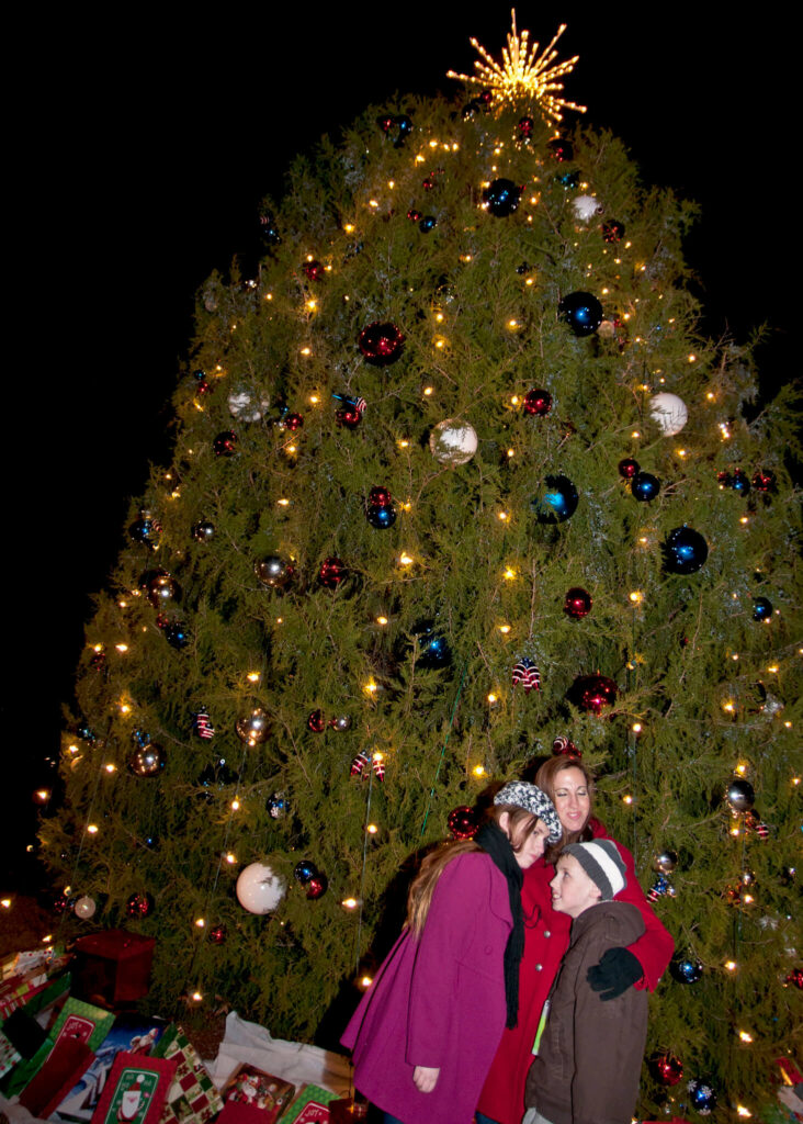 A family by a Christmas tree at the Wheaton Christmas celebration / Flickr / Fort Bragg

Link: https://flickr.com/photos/fortbraggnc/6479299617/in/photolist-7myhzj-aSy6KR-aSy6Qp-aSy7gg-aSy8kK-aSy73n-aSy8wk-aSy7XD-aSy8s8-aSy7uX-aSy7JV-aSy6Fe-aSy7pc-aSy7kx-aSy8g4